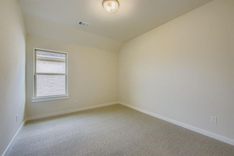 Empty room with light colored carpet and lofted ceiling Empty room with light colored carpet and lofted ceiling
