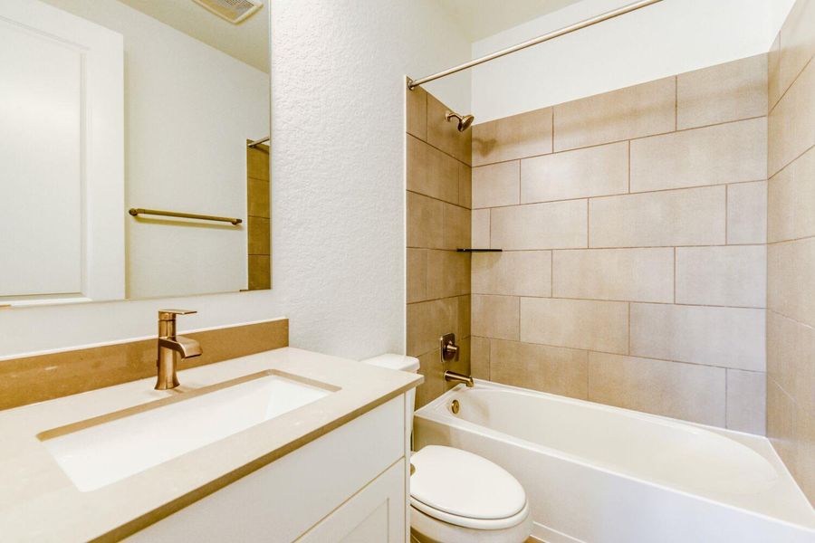 Bathroom featuring a textured wall, vanity, and bathtub / shower combination