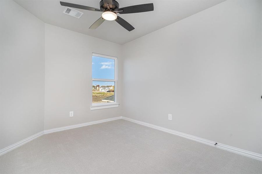 Carpeted spare room featuring ceiling fan