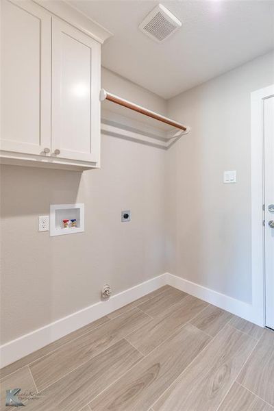 Laundry room with washer hookup, electric dryer hookup, light wood finished floors, and cabinet space
