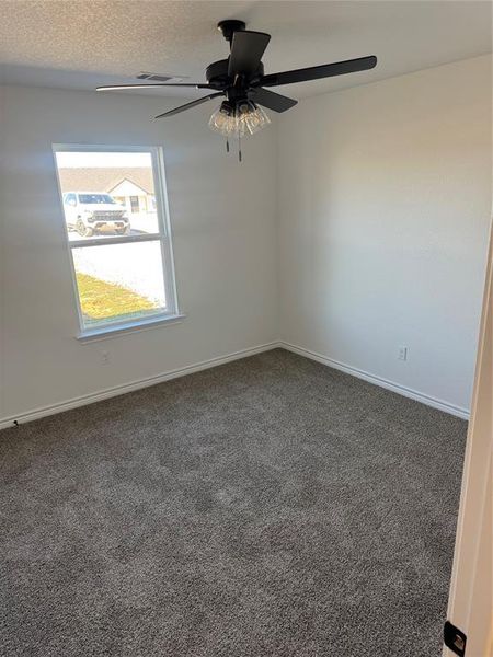 Empty room with ceiling fan and dark carpet