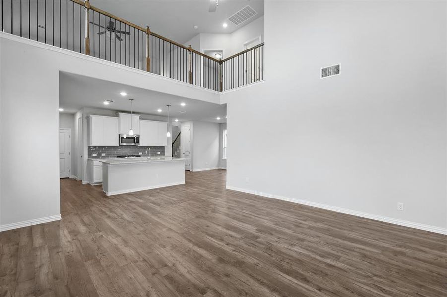 Unfurnished living room with dark wood-type flooring, a high ceiling, and recessed lighting
