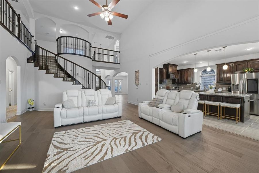 Living room featuring arched walkways, light wood-style flooring, recessed lighting, a towering ceiling, and ceiling fan Living room featuring arched walkways, light wood-style flooring, recessed lighting, a towering ceiling, and ceiling fan