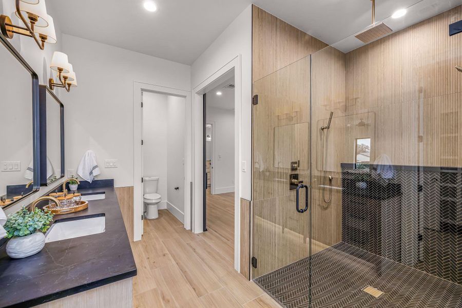 Full bathroom featuring a stall shower, a sink, toilet, and wood finished floors