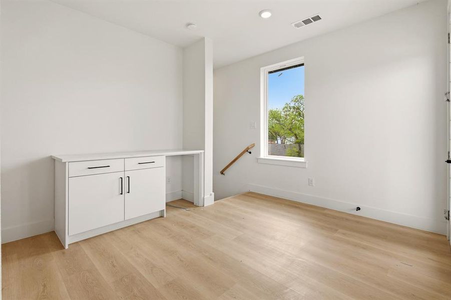 This room features light-toned flooring, a built-in cabinet with black hardware, and a window providing natural light