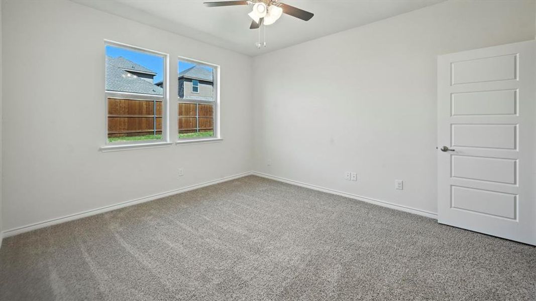 Carpeted empty room with baseboards and ceiling fan Carpeted empty room with baseboards and ceiling fan