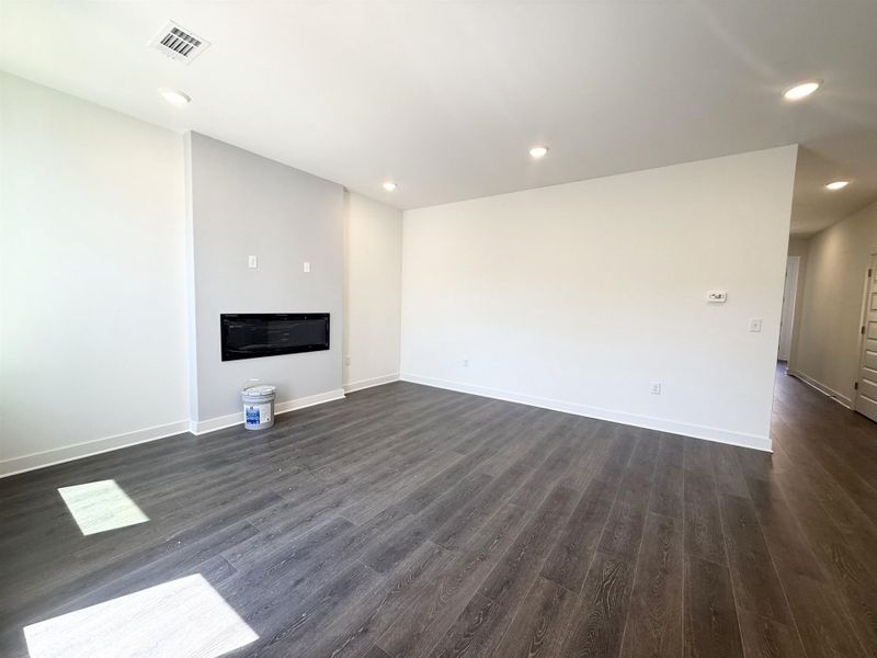 Unfurnished living room featuring recessed lighting and dark wood-style flooring