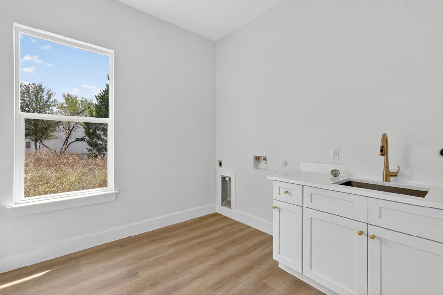 Laundry area with light wood-style flooring, hookup for an electric dryer, washer hookup, and cabinet space