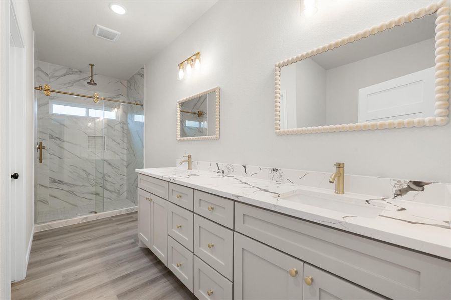 A refined bathroom features a dual vanity with marble-patterned countertops and a spacious, glass-enclosed shower. A refined bathroom features a dual vanity with marble-patterned countertops and a spacious, glass-enclosed shower.