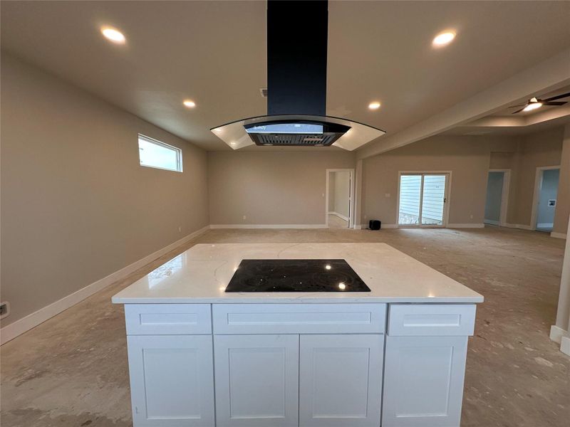 Kitchen featuring island exhaust hood, a center island, open floor plan, white cabinets, and recessed lighting