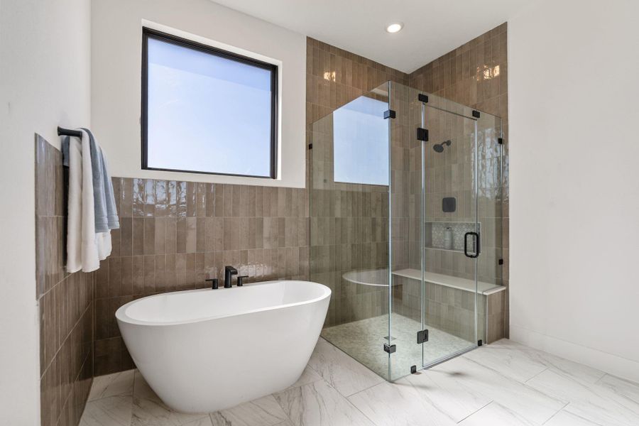 The primary bathroom showcases a sculptural freestanding soaking tub, glass enclosed walk-in shower and refined tile work throughout The primary bathroom showcases a sculptural freestanding soaking tub, glass enclosed walk-in shower and refined tile work throughout