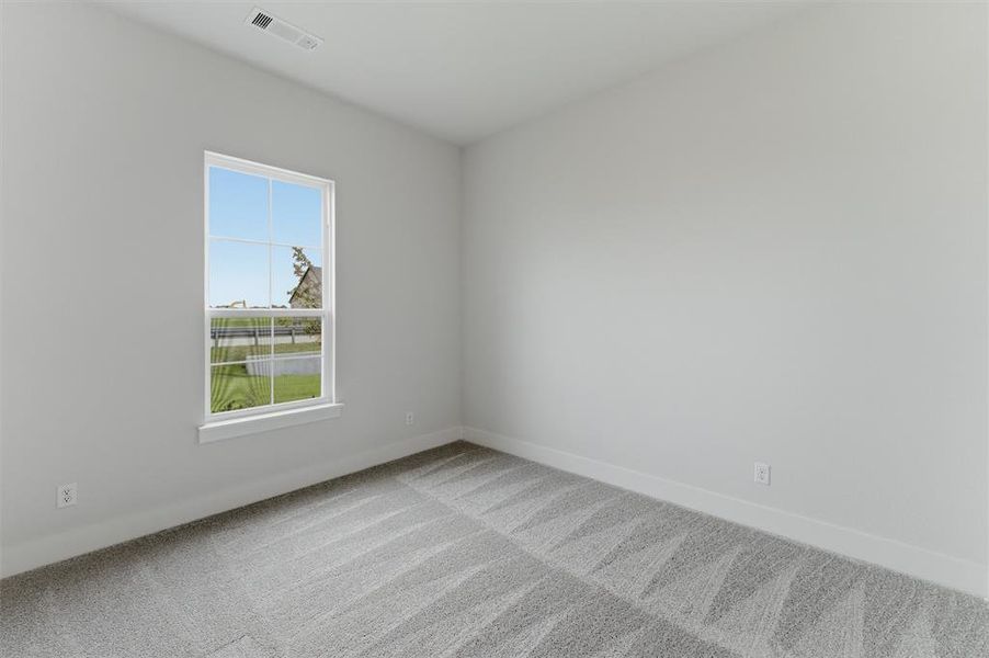 Bright interior space featuring a grid-pattern window, light gray carpet, white baseboards, and a white ceiling with a vent
