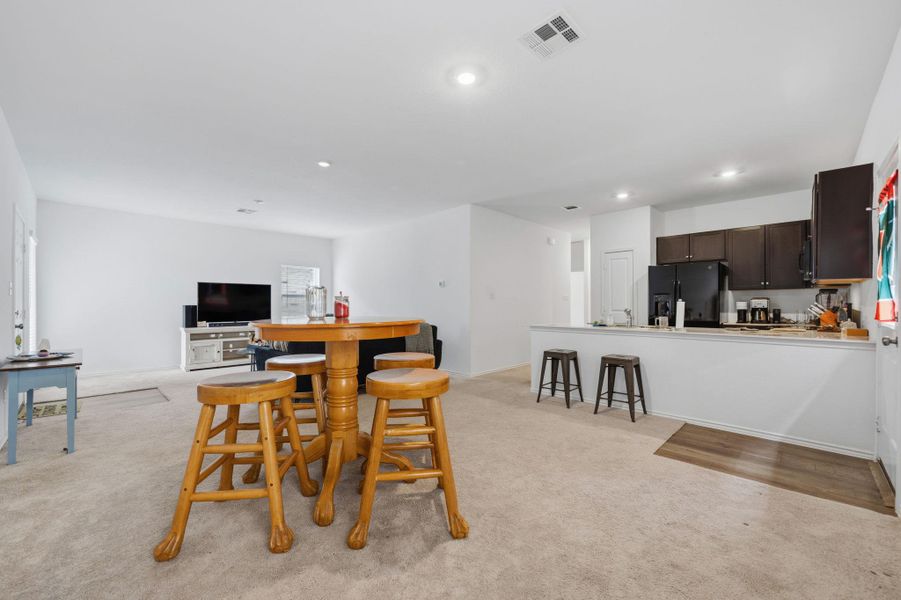 Open-concept living space featuring a partial wall separating the kitchen from the carpeted living area