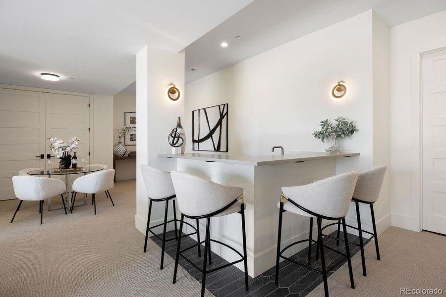 Stylish lower level wet bar with quartz counters and seating for 4.