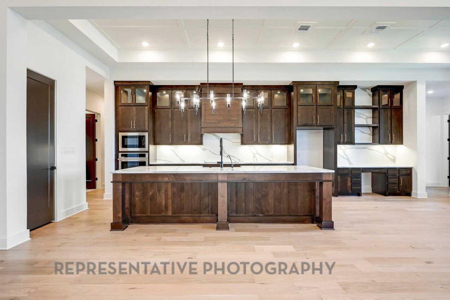 Kitchen with dark brown cabinets, glass insert cabinets, light stone countertops, and recessed lighting Kitchen with dark brown cabinets, glass insert cabinets, light stone countertops, and recessed lighting