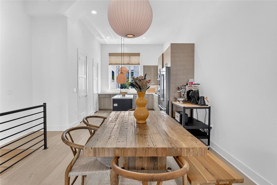 Blonde hardwood floors extend through this airy dining space, leading to a contemporary kitchen.