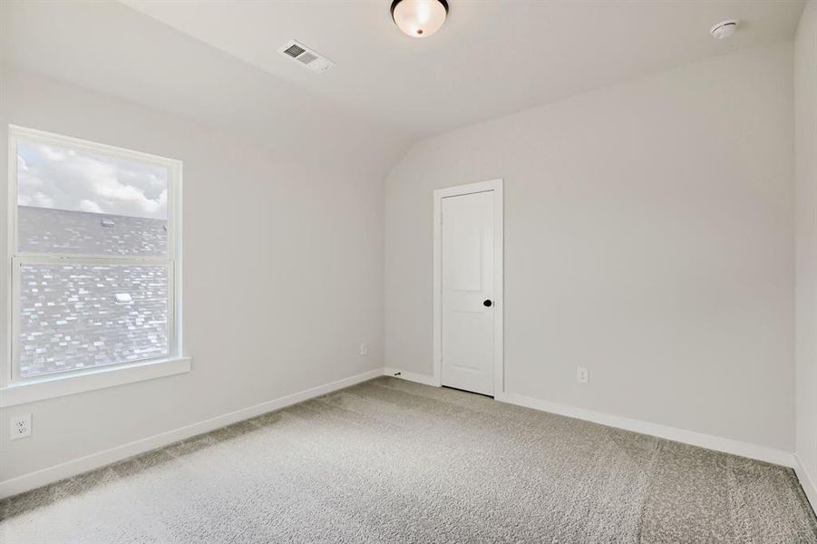 Bedroom featuring neutral wall paint, gray carpeting, white trim, and a prominent window