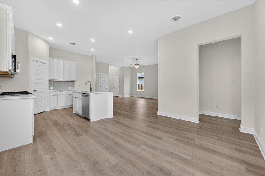 Kitchen featuring open floor plan, backsplash, ceiling fan, a kitchen island with sink, and recessed lighting