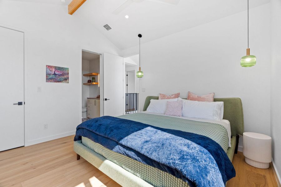Vaulted ceilings showcasing exposed wood beams, light wood-finish flooring, and modern pendant lighting