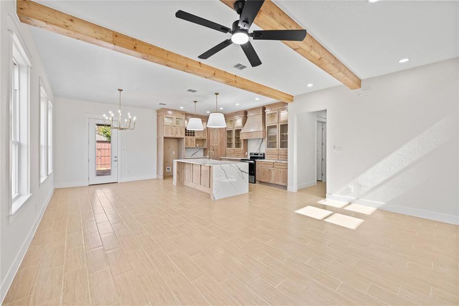 Kitchen with open floor plan, glass fronted cabinets, a chandelier, an island with sink, and beamed ceiling Kitchen with open floor plan, glass fronted cabinets, a chandelier, an island with sink, and beamed ceiling