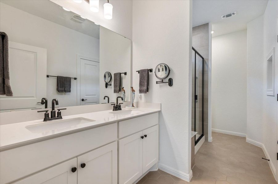 Bathroom featuring double vanity, a stall shower, and light tile patterned floors Bathroom featuring double vanity, a stall shower, and light tile patterned floors