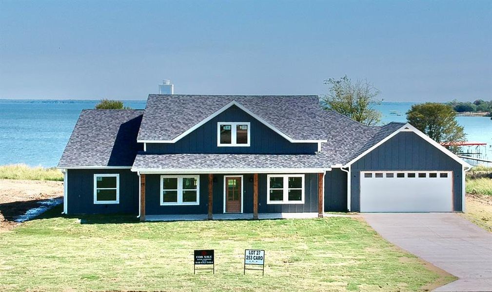 View of front facade featuring a water view, a garage, and a front lawn