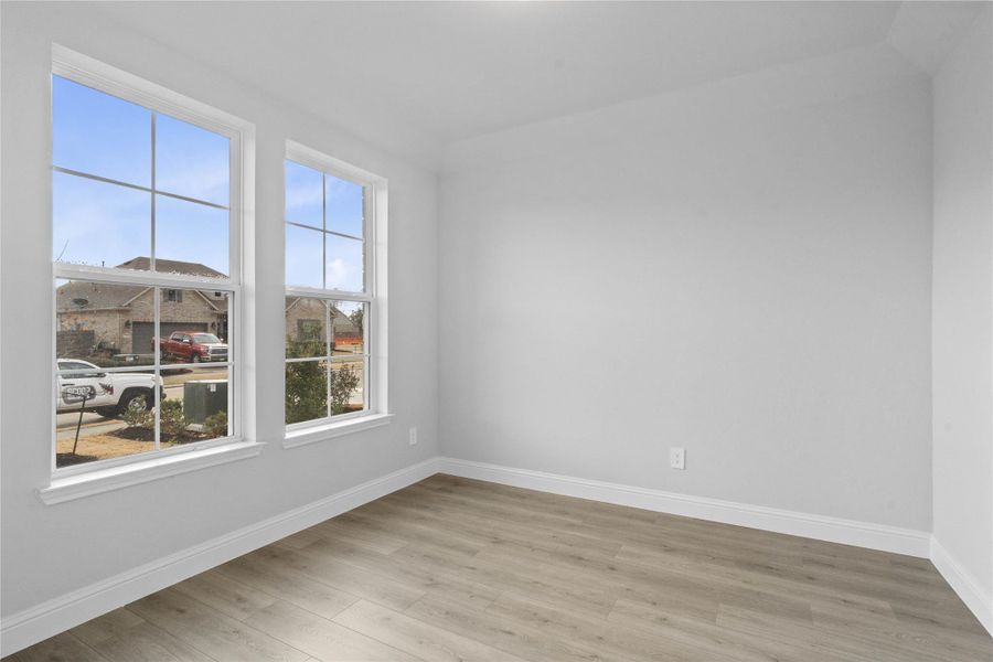 This handsome home office features laminate flooring, large windows, high ceilings, lighting, and custom paint!