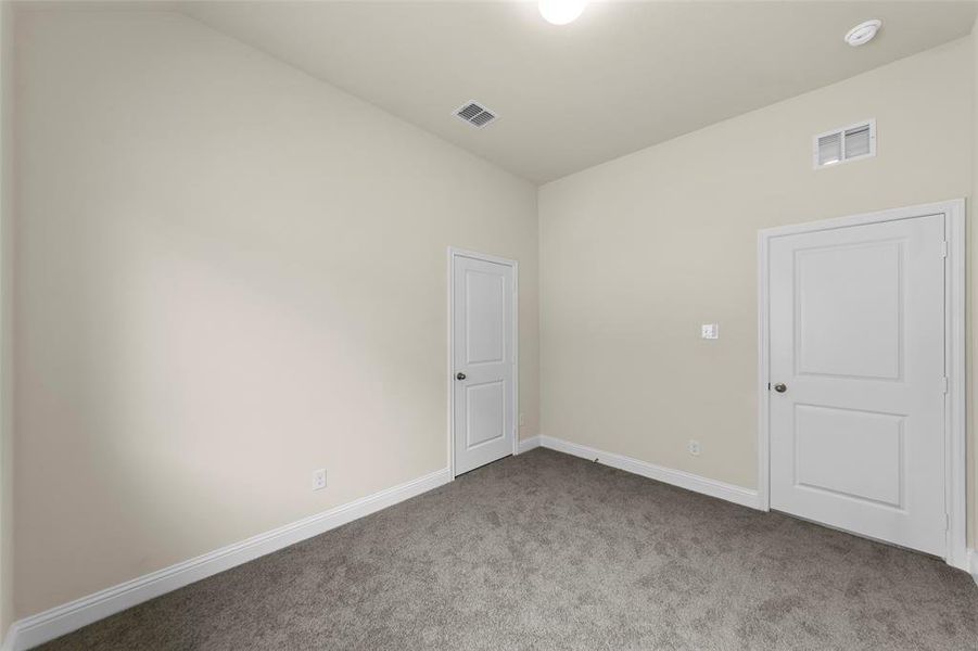 Neutral-toned room featuring a dark gray carpet, white baseboards, and two white paneled doors