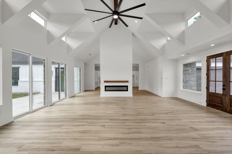 The living space features a sleek double-sided electric fireplace and walls of glass overlooking the backyard, blending indoor and outdoor living beautifully.