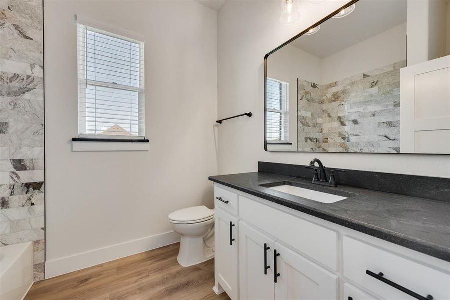 Bathroom featuring a white vanity with dark countertop, a single rectangular sink, and a matte black faucet