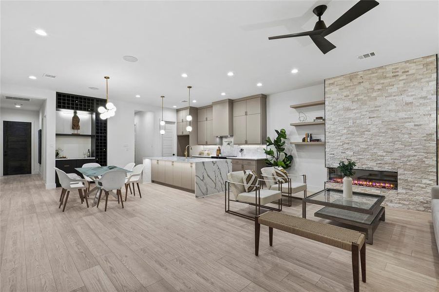 Living room featuring ceiling fan, a stone fireplace, sink, and light hardwood / wood-style floors