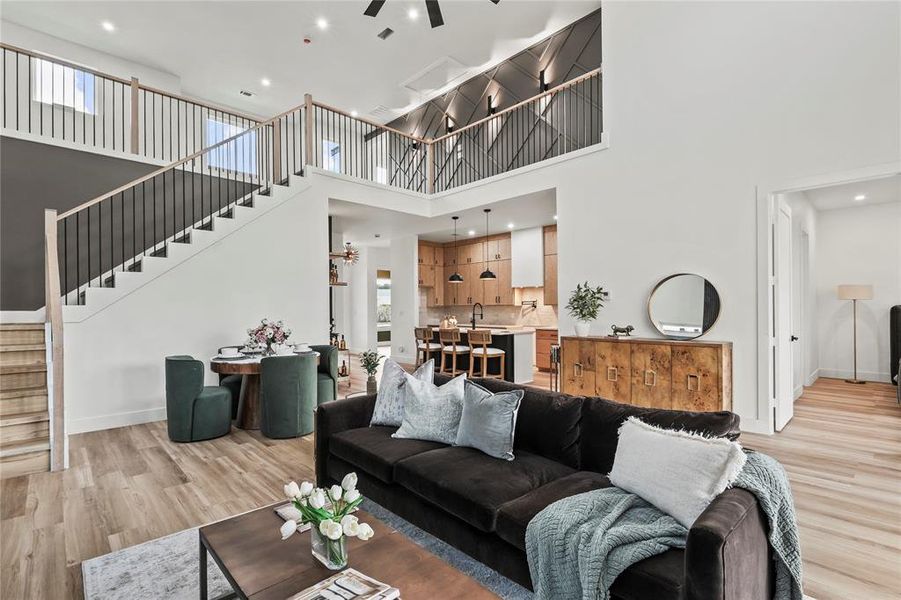 Living area with stairway, light wood-style floors, recessed lighting, a towering ceiling, and a ceiling fan