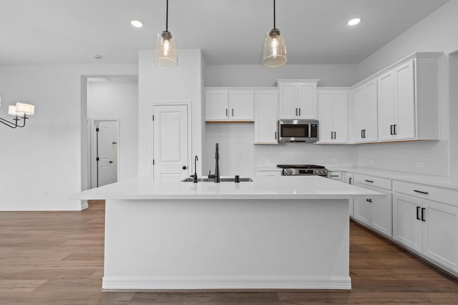 This light and bright kitchen features a large quartz island, white cabinets, a large sink overlooking your family room, recessed lighting, and beautiful backsplash. This light and bright kitchen features a large quartz island, white cabinets, a large sink overlooking your family room, recessed lighting, and beautiful backsplash.