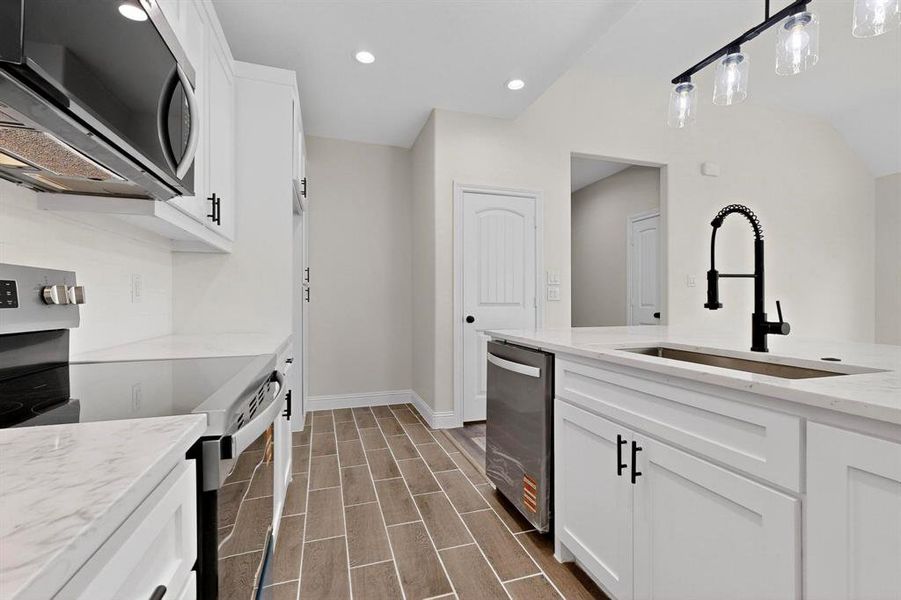 Kitchen with appliances with stainless steel finishes, white cabinets, light stone countertops, recessed lighting, and pendant lighting Kitchen with appliances with stainless steel finishes, white cabinets, light stone countertops, recessed lighting, and pendant lighting