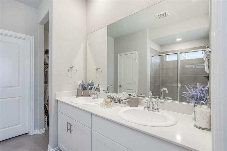 Bathroom with double vanity, tile patterned floors, and a tile shower Bathroom with double vanity, tile patterned floors, and a tile shower