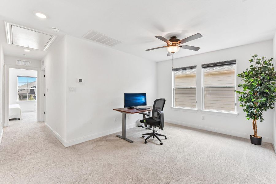 An airy secondary living space, perfect for a home office, offers ample natural light and plush carpeting.