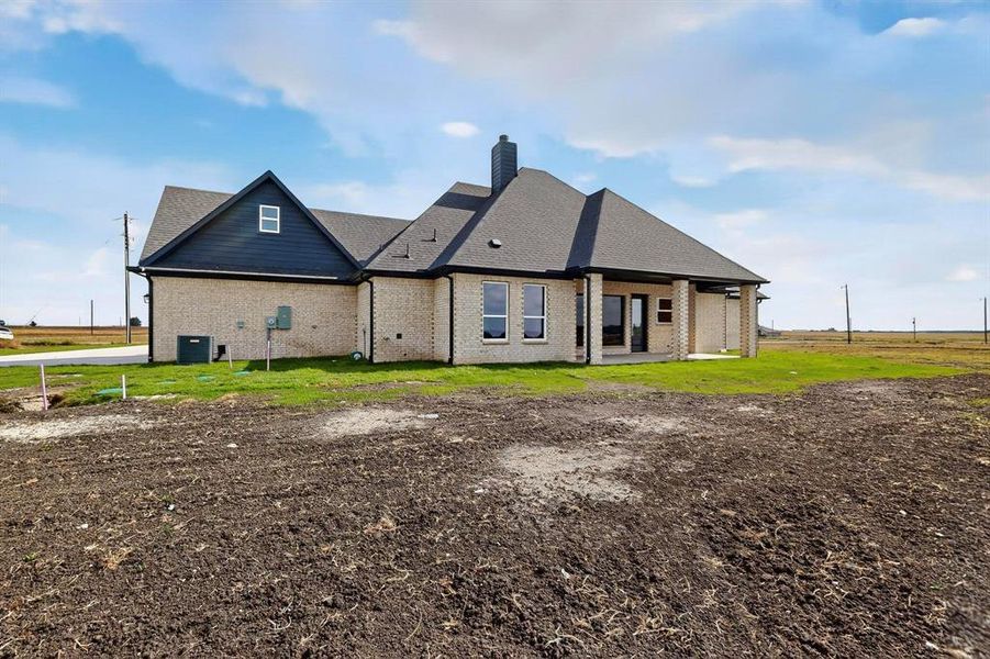 Rear view of house featuring a patio area, brick siding, a chimney, and a yard Rear view of house featuring a patio area, brick siding, a chimney, and a yard