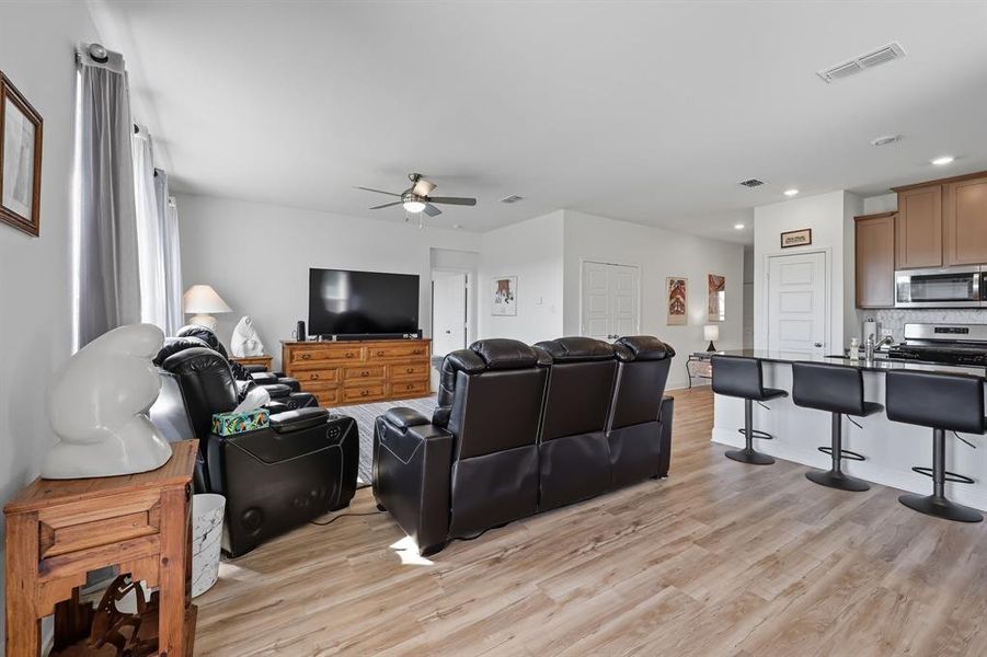 Living room featuring light wood-type flooring, recessed lighting, and a ceiling fan Living room featuring light wood-type flooring, recessed lighting, and a ceiling fan