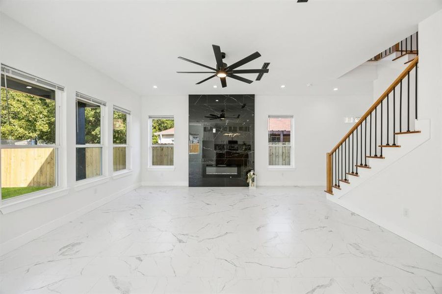 Unfurnished living room with healthy amount of natural light, light marble finish flooring, stairs, and recessed lighting