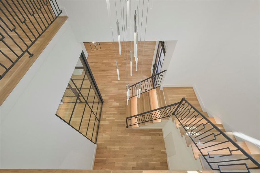 View from the top of the stairs. The graceful pendent chandelier accents the two-story entry.