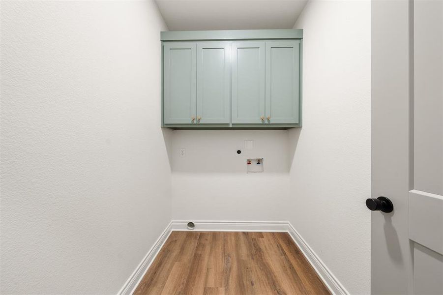 Washroom with light wood-style flooring, cabinet space, hookup for a washing machine, and electric dryer hookup Washroom with light wood-style flooring, cabinet space, hookup for a washing machine, and electric dryer hookup