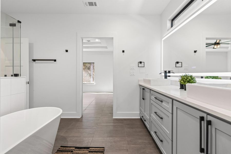 Bathroom with a soaking tub, double vanity, a shower stall, a tray ceiling, and ceiling fan