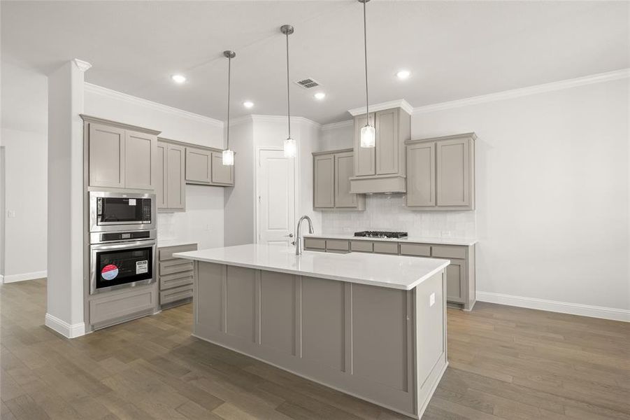 Kitchen with stainless steel appliances, gray cabinets, crown molding, decorative backsplash, and baseboards Kitchen with stainless steel appliances, gray cabinets, crown molding, decorative backsplash, and baseboards