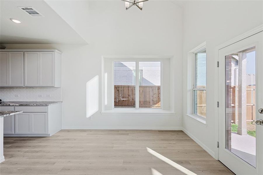 Unfurnished living room featuring light hardwood / wood-style flooring, ceiling fan with notable chandelier, and a towering ceiling