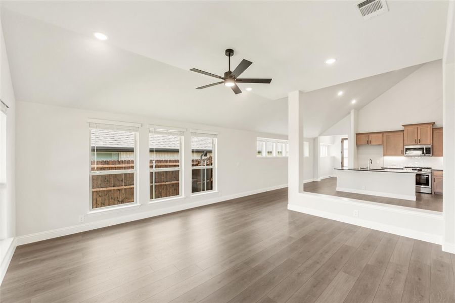 Open living room with hardwood floors and ceiling fan, open to kitchen with wood cabinets and stainless appliances Open living room with hardwood floors and ceiling fan, open to kitchen with wood cabinets and stainless appliances
