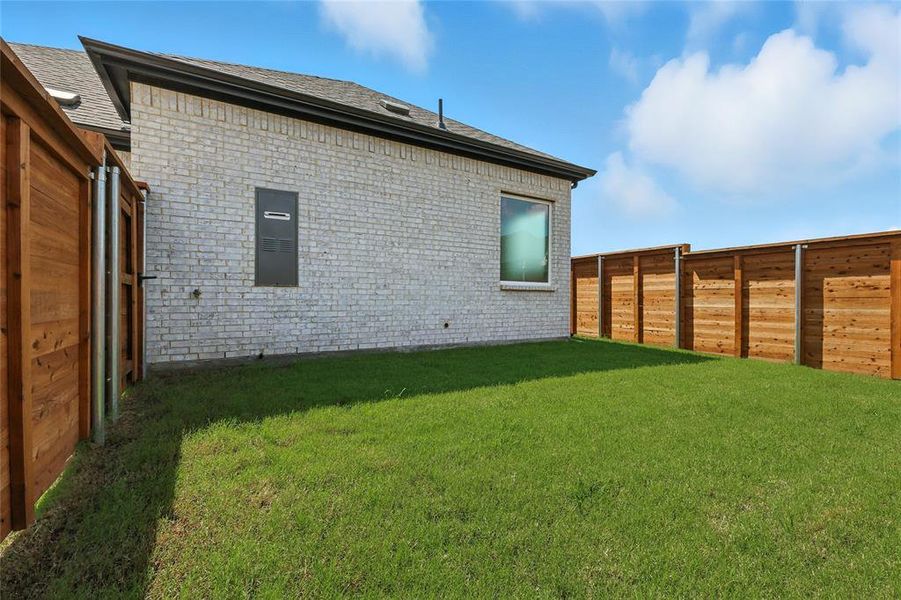 Back of property featuring brick siding, a fenced backyard, and roof with shingles