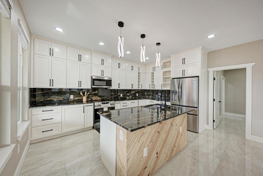 Gleaming stone countertops and a central wood-paneled island define this modern culinary workspace. Gleaming stone countertops and a central wood-paneled island define this modern culinary workspace.