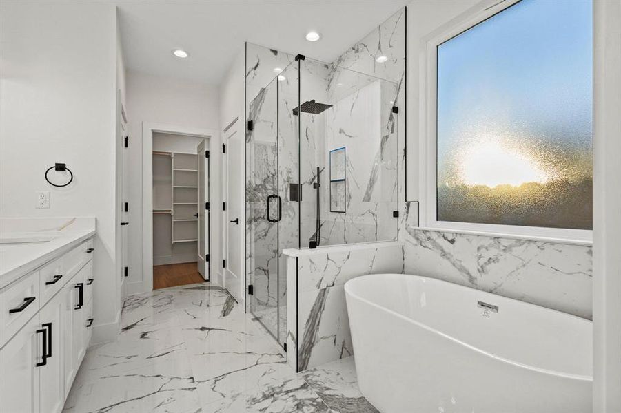 Full bathroom with vanity, a freestanding bath, a walk in closet, light marble finish flooring, and recessed lighting