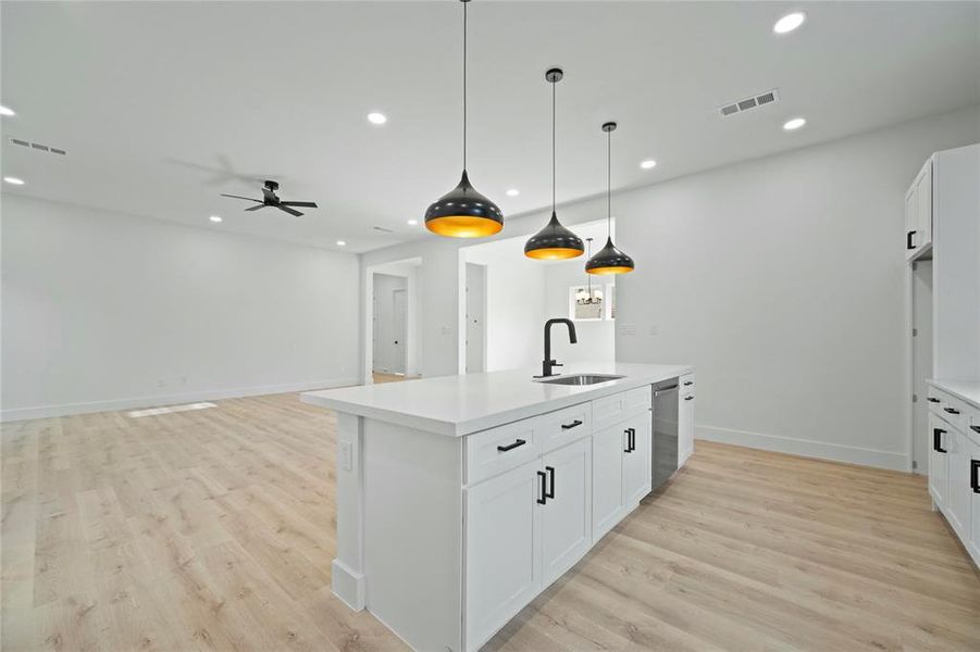 Kitchen featuring stainless steel dishwasher, recessed lighting, a center island with sink, a ceiling fan, and light countertops