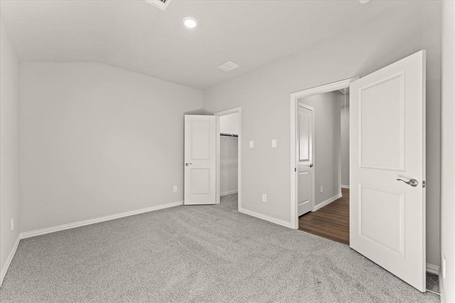 Unfurnished bedroom with carpet and lofted ceiling